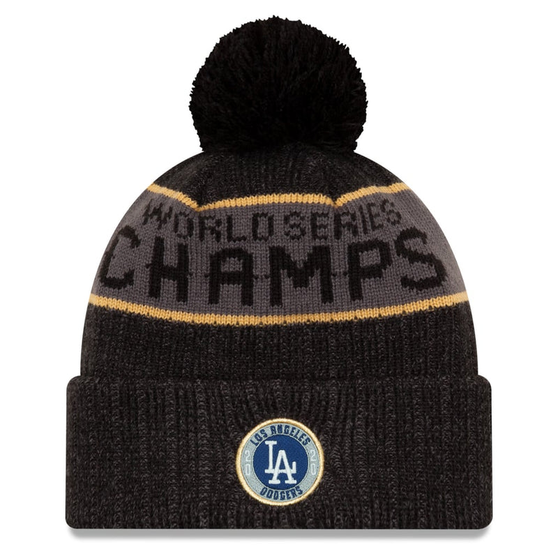Load image into Gallery viewer, A black knit pom-pom beanie with a gray and gold stripe and 'WORLD SERIES CHAMPS' text, featuring a Los Angeles Dodgers logo patch on the front cuff.
