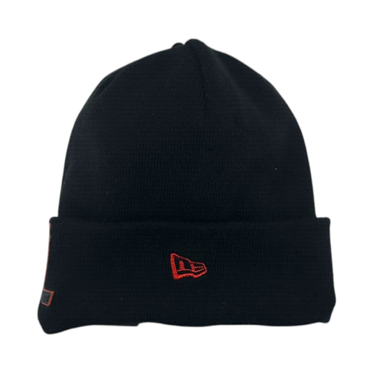 A black knit beanie hat with a folded cuff, featuring a red embroidered New Era flag logo on the front and a small side tag.