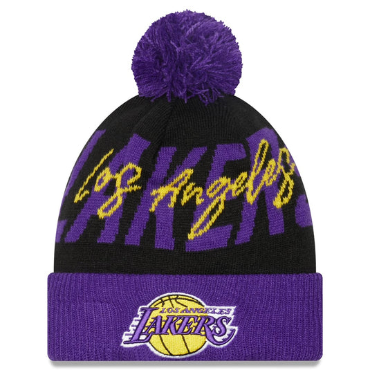 A Los Angeles Lakers knit pom-pom beanie featuring a black upper section with purple and yellow 'Los Angeles' script, a purple pom-pom, and a purple cuff with the Lakers logo.