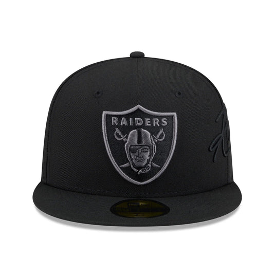 A black fitted baseball cap featuring the embroidered Oakland Raiders shield logo on the front, with a tonal black script logo on the side, photographed against a plain white background.