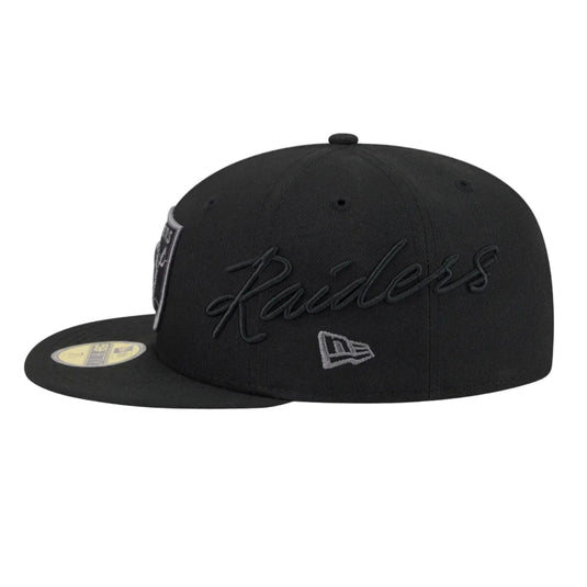The left side of the New Era Raiders Side Script Cap featuring "Raiders" embroidered in black right above the New Era logo in Gray.