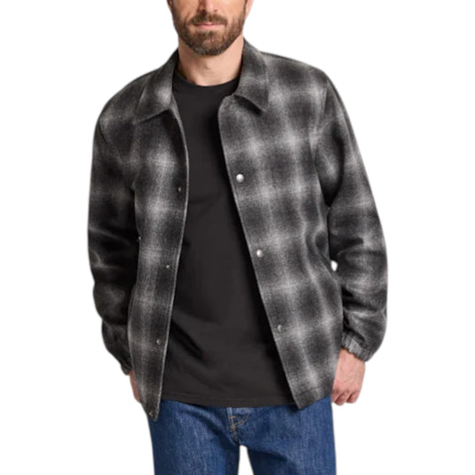 Man wearing a gray plaid shirt over a black t-shirt on a white background