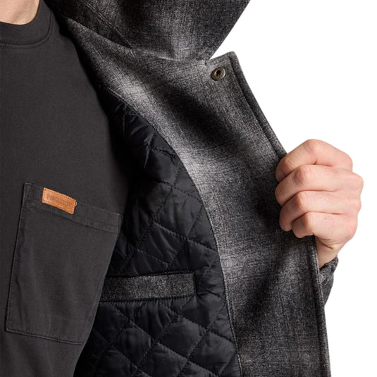 Person wearing a black quilted jacket with a brand logo on a white background