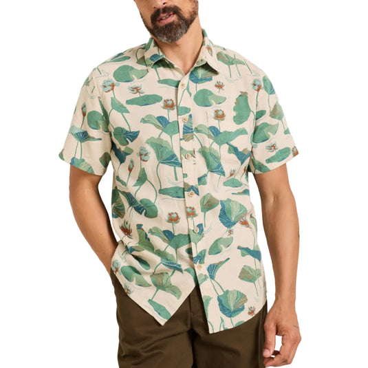 Man wearing a short-sleeve shirt with a tropical leaf pattern against a plain background