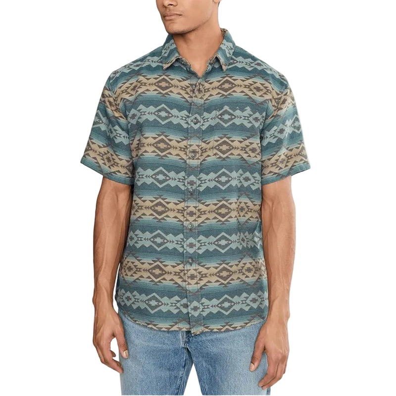 Load image into Gallery viewer, A man wearing a short-sleeve button-up shirt with a blue, beige, and gray geometric pattern, paired with blue jeans, against a plain white background.

