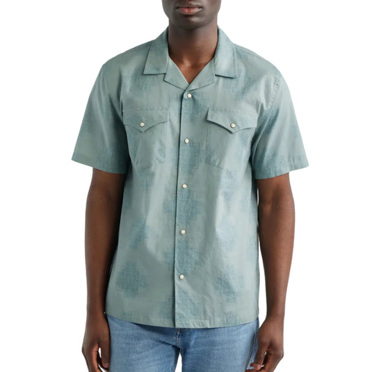 Model in a light green patterned button up shirt with snap button closures