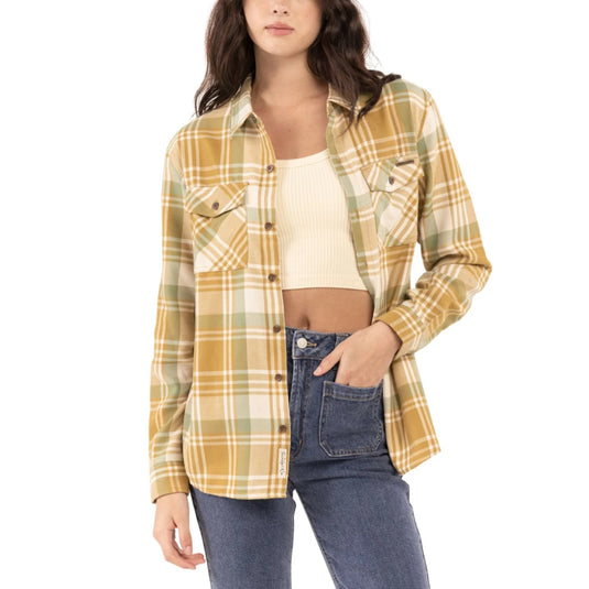 Woman wearing a gold plaid shirt over a crop top on a white background