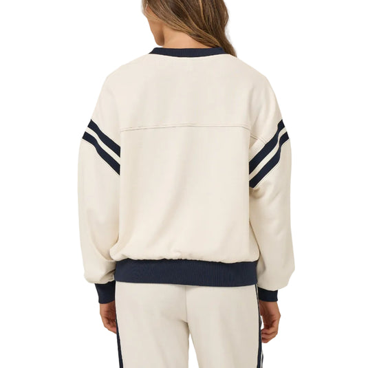 Person wearing a cream tracksuit with navy accents on a plain background