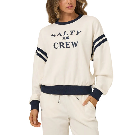 Woman wearing a 'Salty Crew' sweatshirt on a beige background
