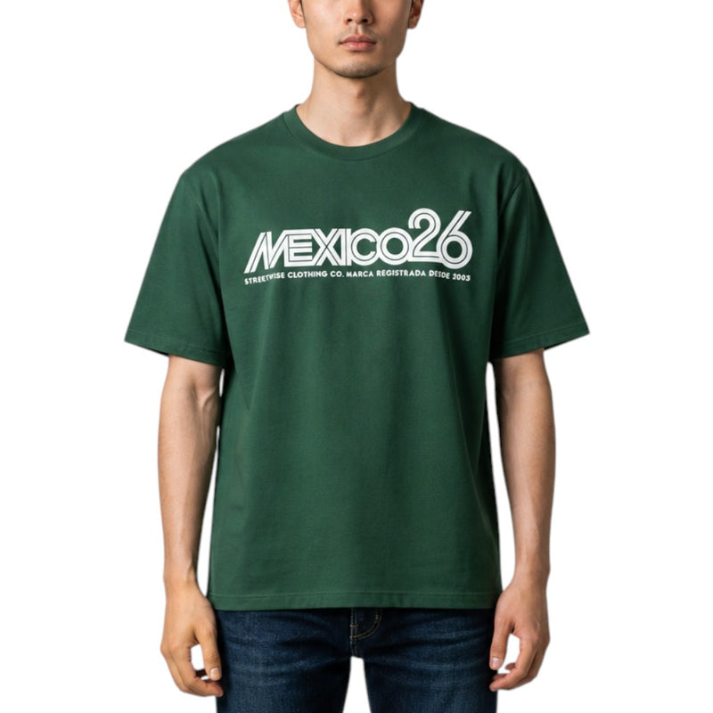 Load image into Gallery viewer, A man wearing a dark green crewneck t-shirt with a white 'MEXICO26' graphic printed across the chest, paired with dark blue jeans, against a plain white background.
