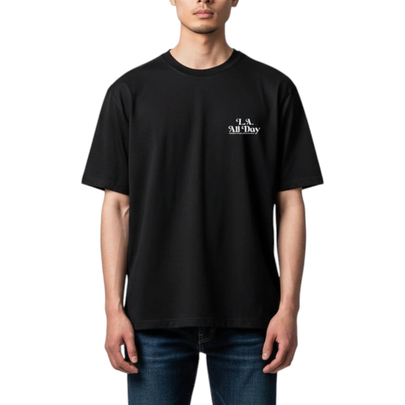 Load image into Gallery viewer, A man wearing a black short-sleeve t-shirt with a small white 'All Day' graphic on the left chest, paired with blue jeans, against a plain white background.
