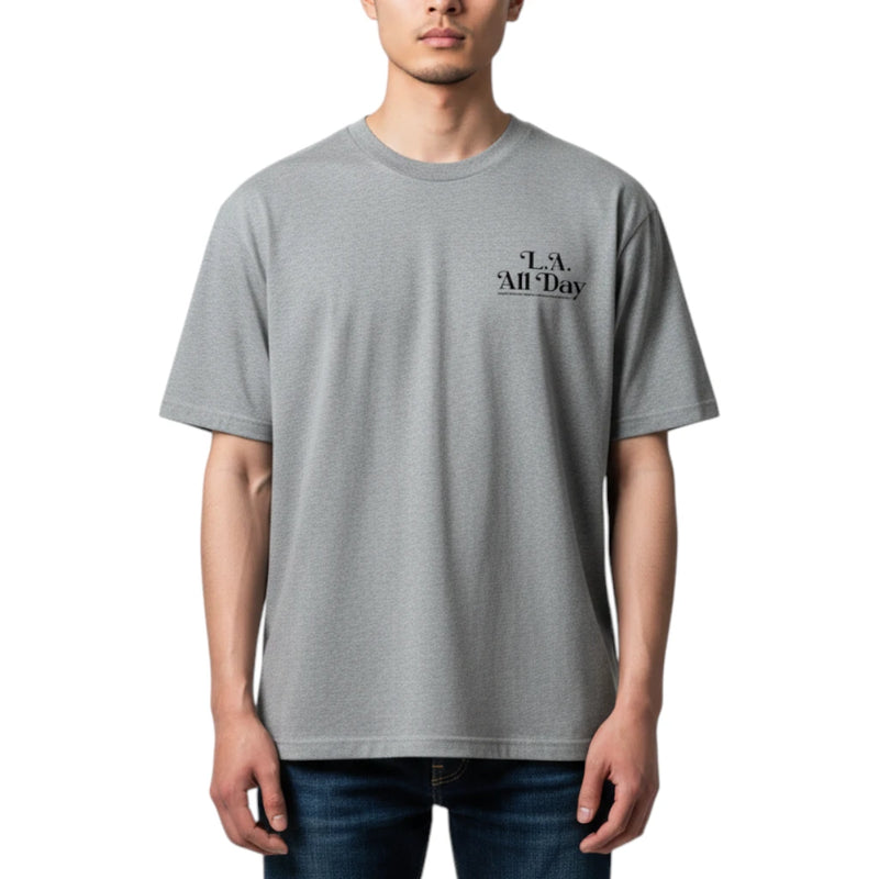 Load image into Gallery viewer, A man wearing a light gray crewneck t-shirt with a small black graphic on the left chest that reads 'L.A. All Day'.
