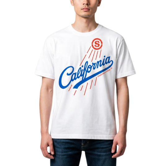 A man wearing a white short-sleeve t-shirt with a blue and red 'California' graphic on the front, paired with dark blue jeans, against a plain white background.