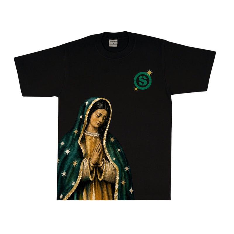 Load image into Gallery viewer, A black short-sleeve t-shirt featuring a graphic print of the Virgin of Guadalupe on the front, with a green circular 'S' logo on the left chest, displayed against a solid white background.

