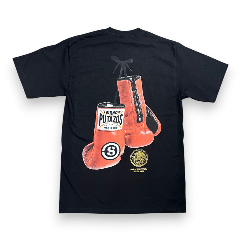 Load image into Gallery viewer, A black short-sleeve t-shirt shown from the back, featuring a large graphic print of red boxing gloves with 'Tiranda Putazos' branding and a small gold circular emblem below.
