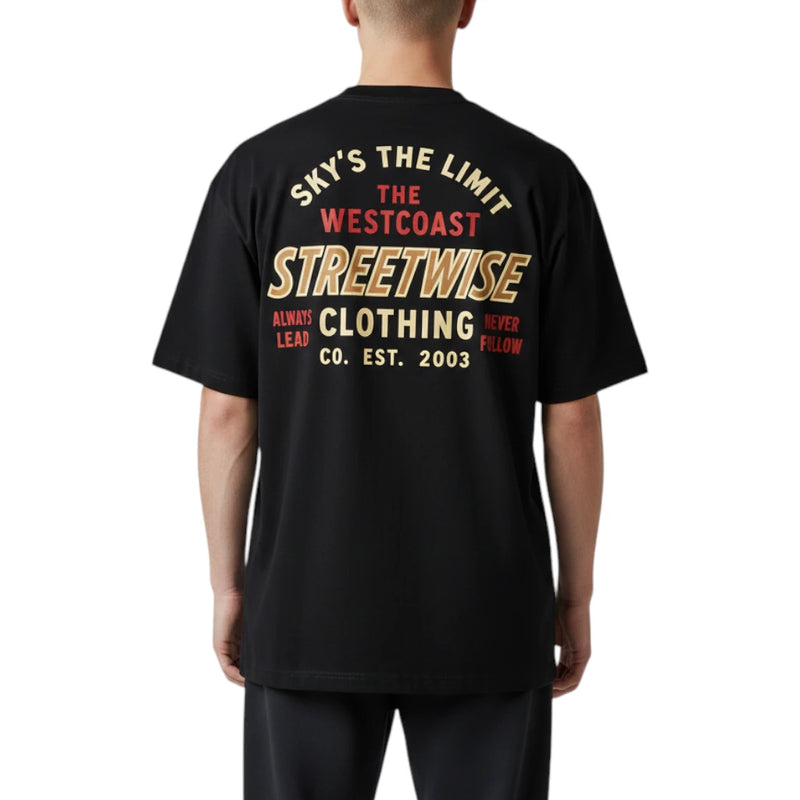 Load image into Gallery viewer, A person shown from the back wearing a black short-sleeve T-shirt with a large multicolor graphic print on the back. The text includes 'SKY'S THE LIMIT', 'THE WESTCOAST', 'STREETWISE'.
