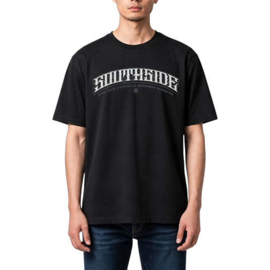 A man wearing a black short-sleeve t-shirt with a white arched 'SOUTHSIDE' graphic and smaller text underneath, paired with blue jeans, against a plain white background.