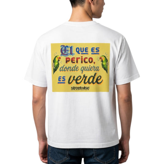 A man wearing a white t-shirt, viewed from the back. The shirt features a large graphic print with Spanish text 'El que es perico, donde quiera es verde' in blue and black lettering over a yellow background, flanked by two green parrots.