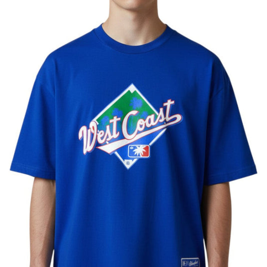 Person wearing a royal blue t-shirt with 'West Coast' logo on a white 