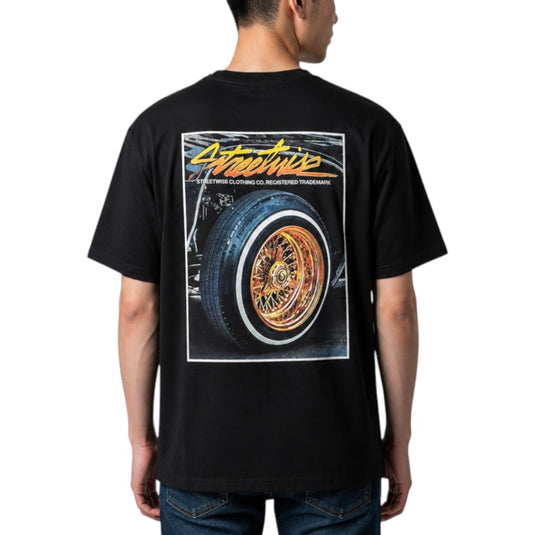 A man wearing a black t-shirt from the back, featuring a large graphic print of a custom car wheel with the word 'Streetwise' in yellow script.
