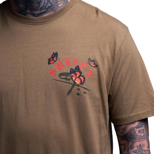 A close-up of a person wearing a brown short-sleeve t-shirt with a graphic on the chest featuring orange and black butterflies and red text.