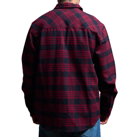 A man viewed from the back wearing a long-sleeve plaid flannel shirt in dark red and navy blue, paired with blue jeans against a plain white background.