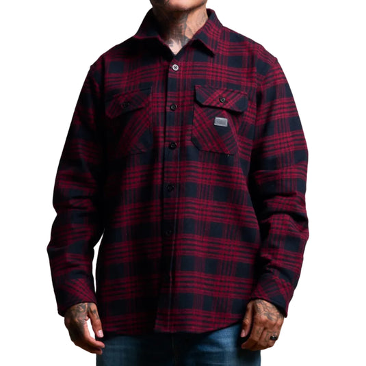 A man wearing a long-sleeve red and black plaid flannel shirt with two chest pockets, shown from the neck down against a plain white background.