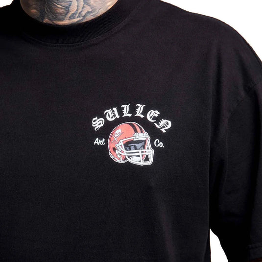 A close-up of a black t-shirt worn by a tattooed model. The shirt features a graphic on the chest with the text 'SULLEN Art Co.