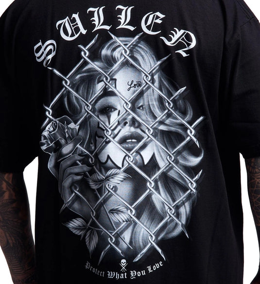 A close-up of a black graphic t-shirt featuring a detailed grayscale illustration of a woman's face behind a chain-link fence, with the word 'SULLEN' in white gothic lettering at the top.