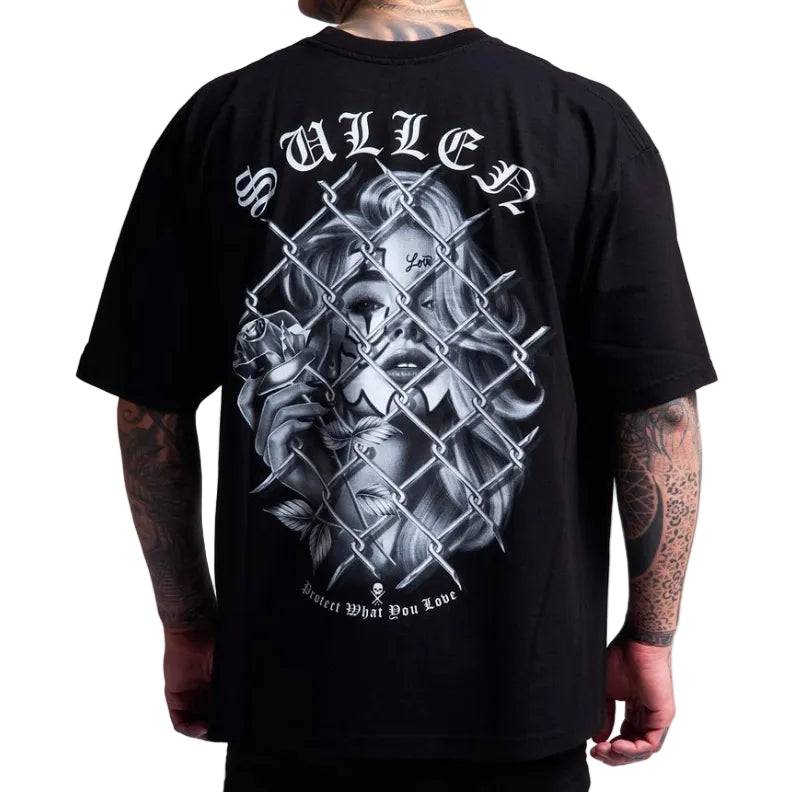 Load image into Gallery viewer, A man wearing a black t-shirt, viewed from the back. The shirt features a large graphic print of a skull and a woman behind a chain-link fence, with the word 'SULLEN' in a gothic font above and 'Protect What You Love!' below.
