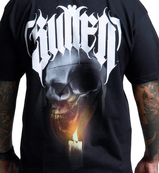 A black short-sleeve graphic t-shirt featuring a large white gothic-style logo across the chest and a detailed skull print with a glowing candle flame in the lower front, shown on a model with tattooed arms against a white background.