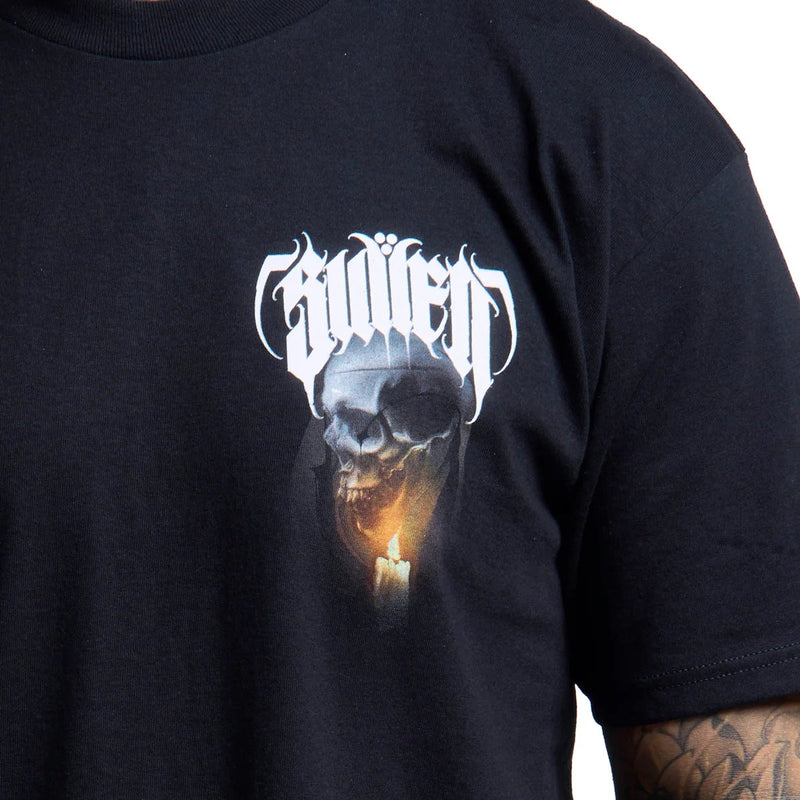 Load image into Gallery viewer, Close-up of a black t-shirt featuring a graphic print of a skull with a glowing candle and the word 'Sullen' in a white gothic font, worn by a person with a visible tattooed arm.
