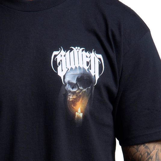 Close-up of a black t-shirt featuring a graphic print of a skull with a glowing candle and the word 'Sullen' in a white gothic font, worn by a person with a visible tattooed arm.