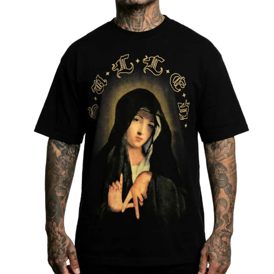 A black short-sleeve graphic t-shirt featuring a print of a religious figure resembling Santa Muerte, with gold gothic lettering arching over the image. The shirt is shown on a model with tattooed arms against a plain white background.