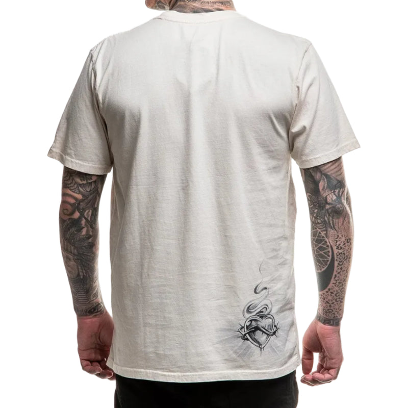 Load image into Gallery viewer, Person wearing a beige t-shirt with a design on the back, showing tattoos on arms.
