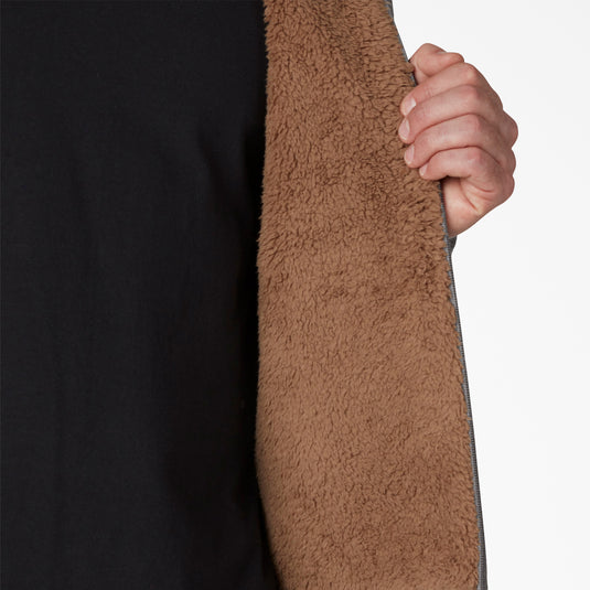 Close-up of a hand holding a brown textured fabric against a black background